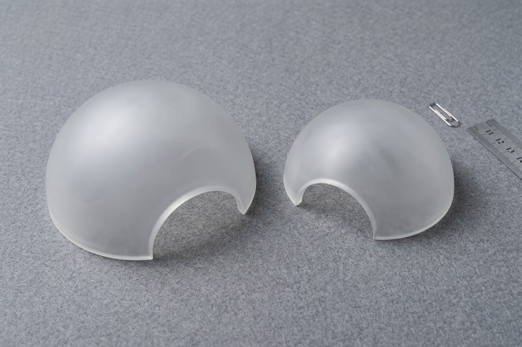 Two fine-ground frosted domes of different sizes next to a paper clip