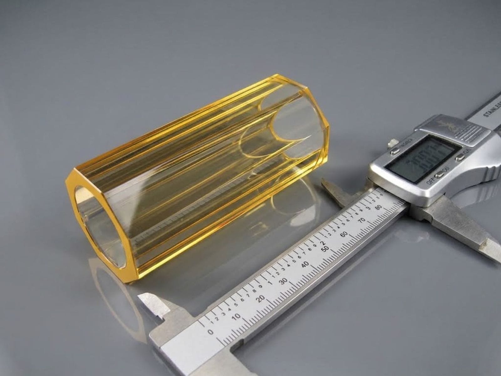 Octagonal yellow glass flow tube next to a digital caliper