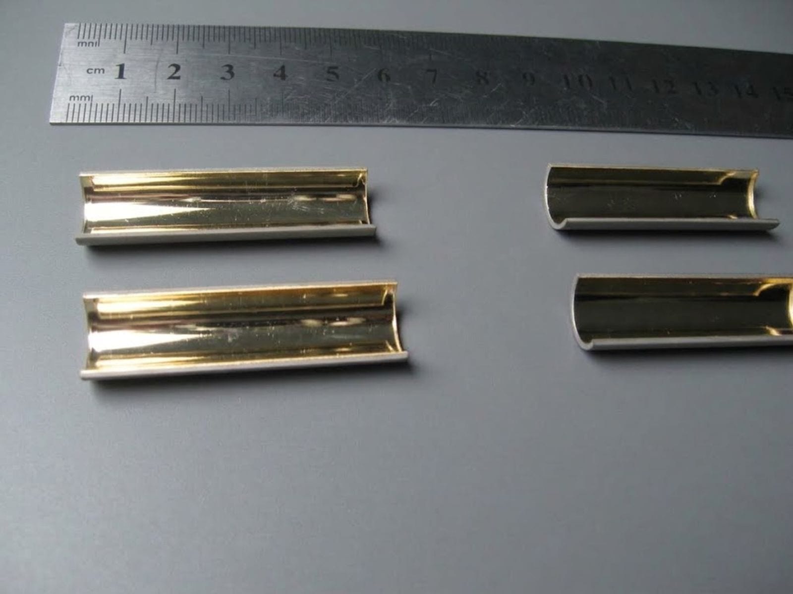 Gold-coated half-cylinder reflectors next to a ruler