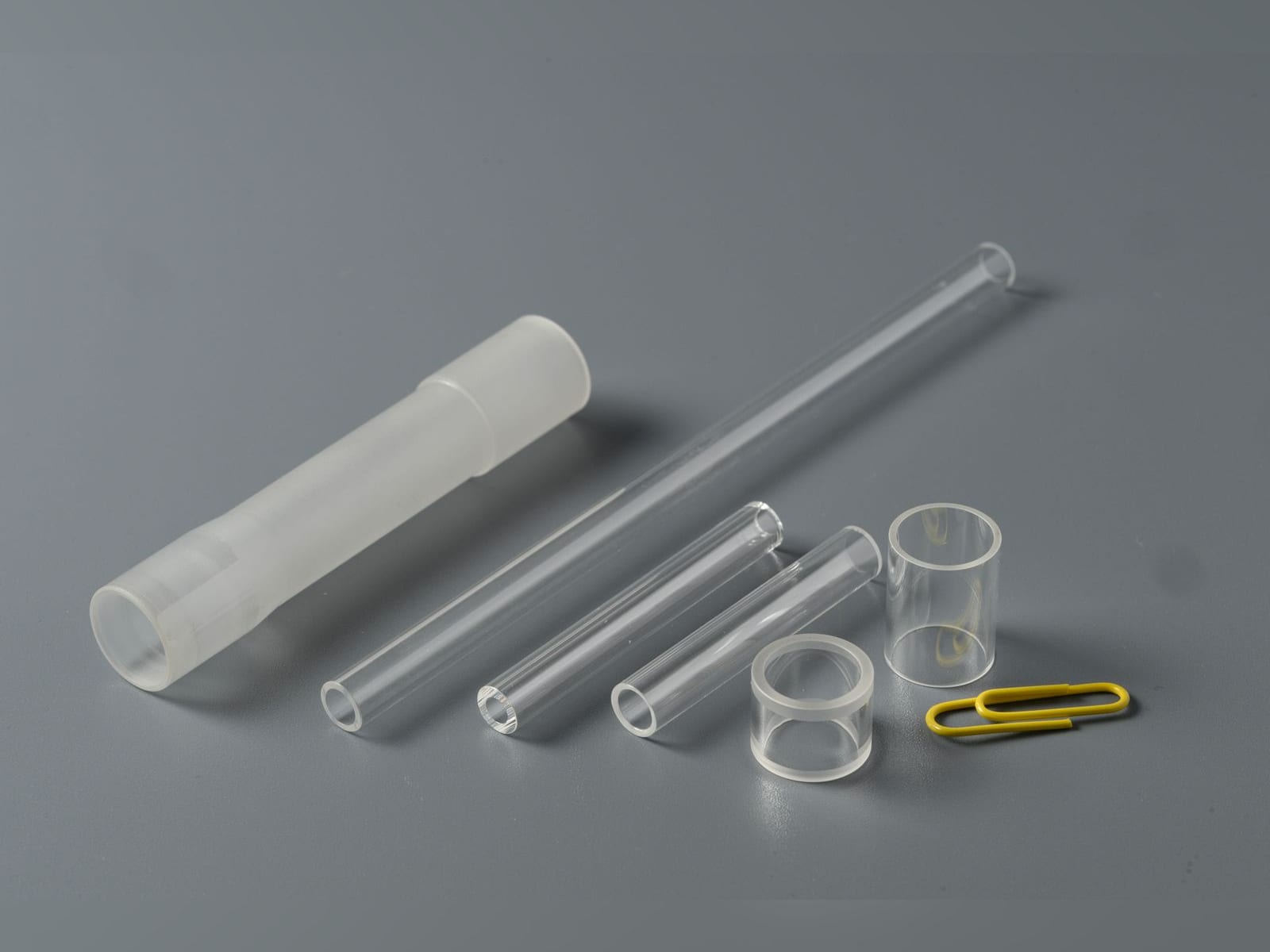 Round glass flow tubes and rings next to a paper clip