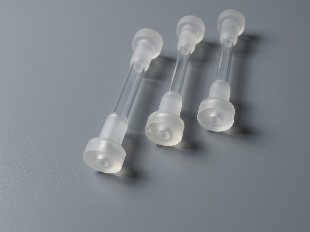 Three custom-machined components with fluted caps and cylindrical shafts