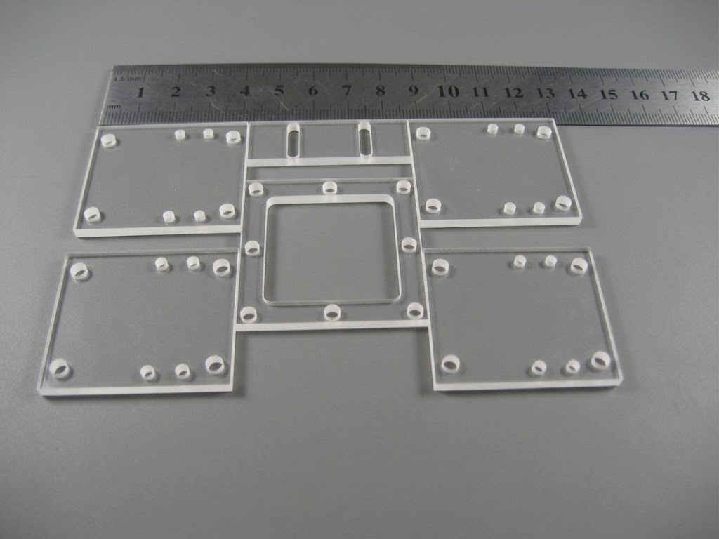 Set of custom-cut mounting plates with drilled and stepped bores measured against a ruler