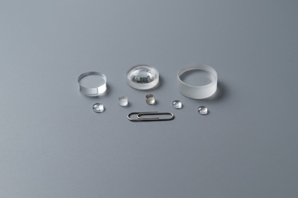 Range of spherical lenses and cylinders of different sizes next to a paper clip