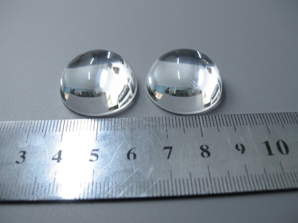 Two polished plano-convex lenses next to a ruler