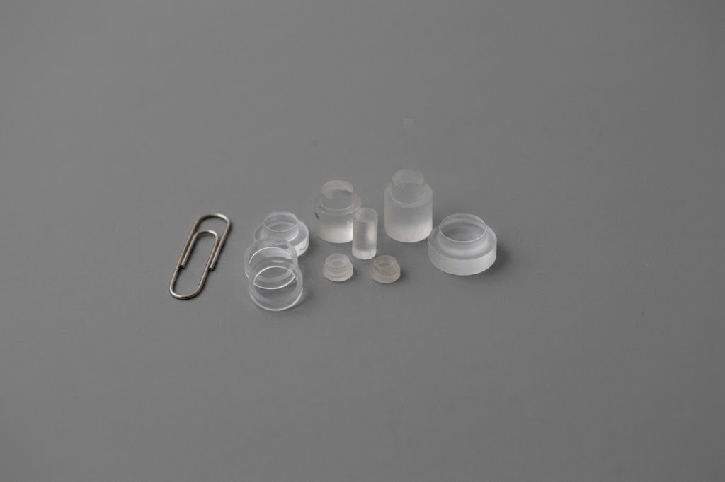 Assortment of small sapphire stepped window parts next to a paperclip